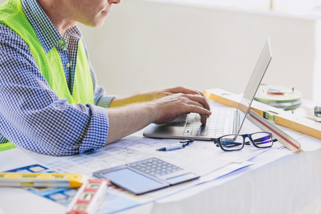 Construction engineer builder working at desk typing on laptop computer